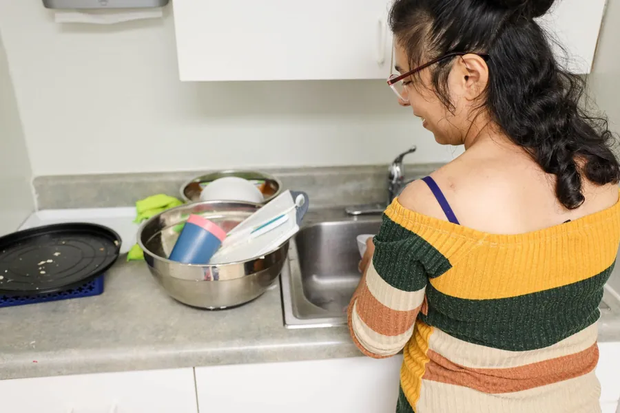 A participant preparing food in a kitchen during a home services session